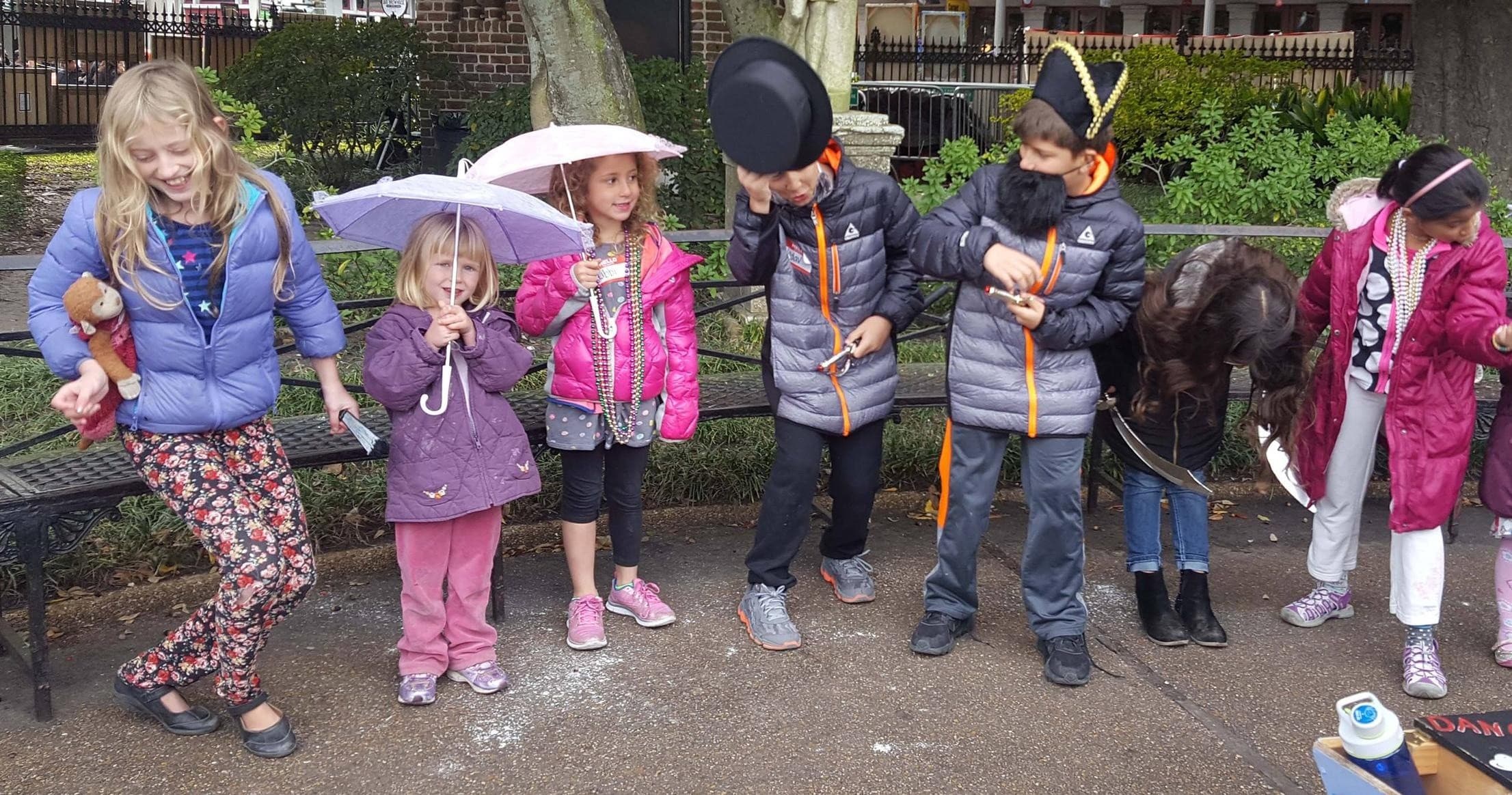 Children in jackets on park path wearing hats during city tour
