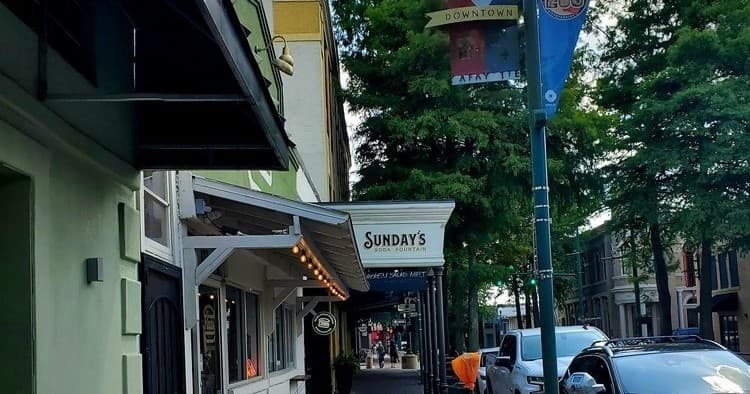 Downtown street storefronts and sidewalk dining under trees