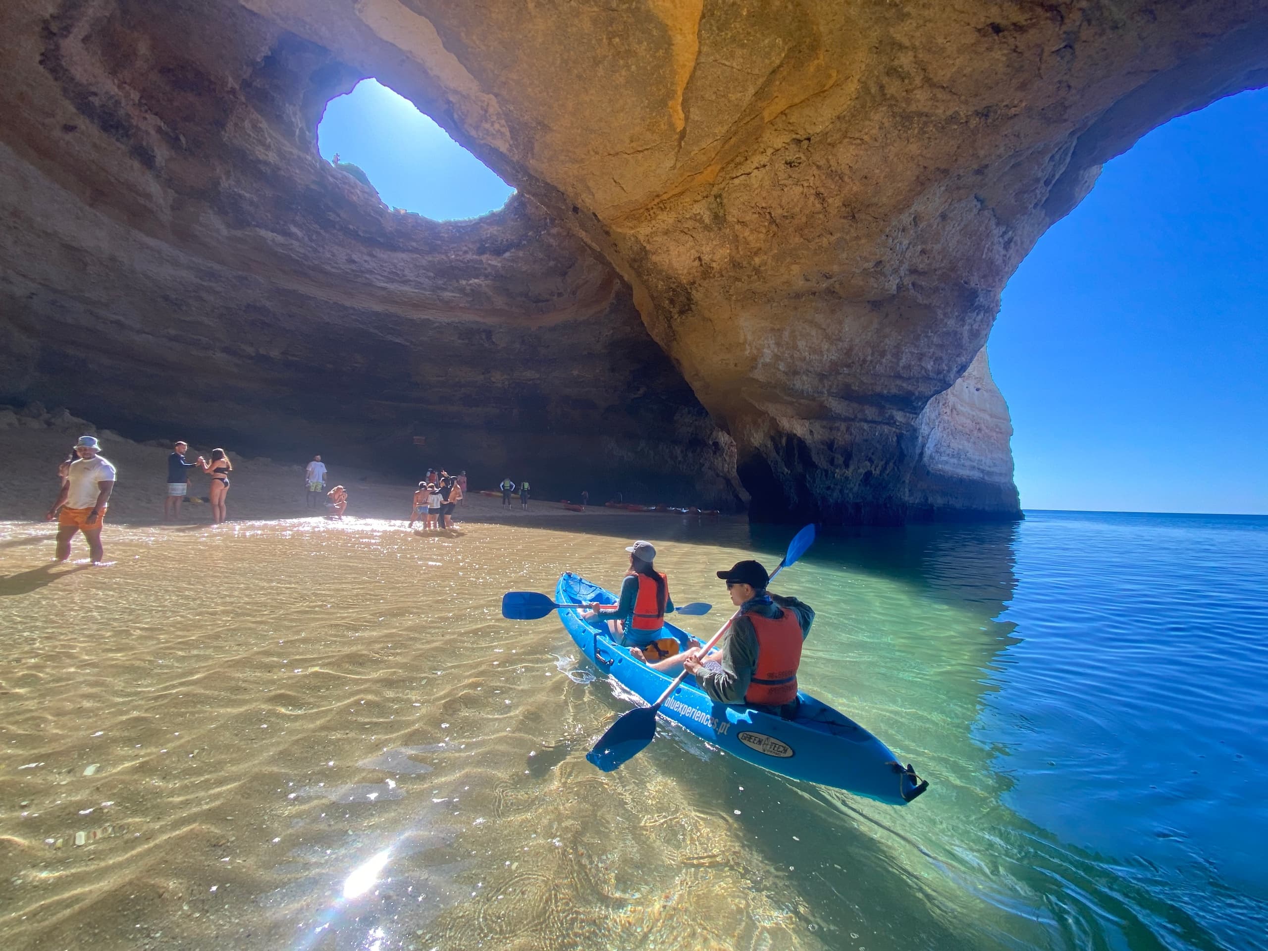 Two kayakers paddling in clear tidal pool inside sea cave