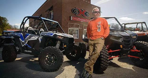 Guide posing with off-road UTVs outside Crazy Mountain Cycles shop