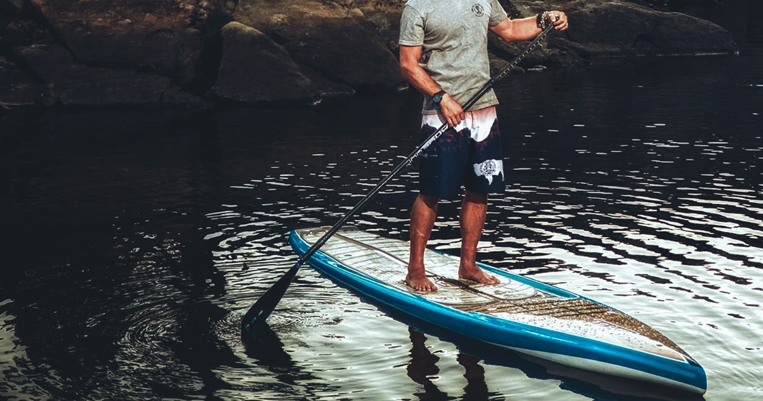 Standup paddleboarding on tranquil lake shore, solo paddler