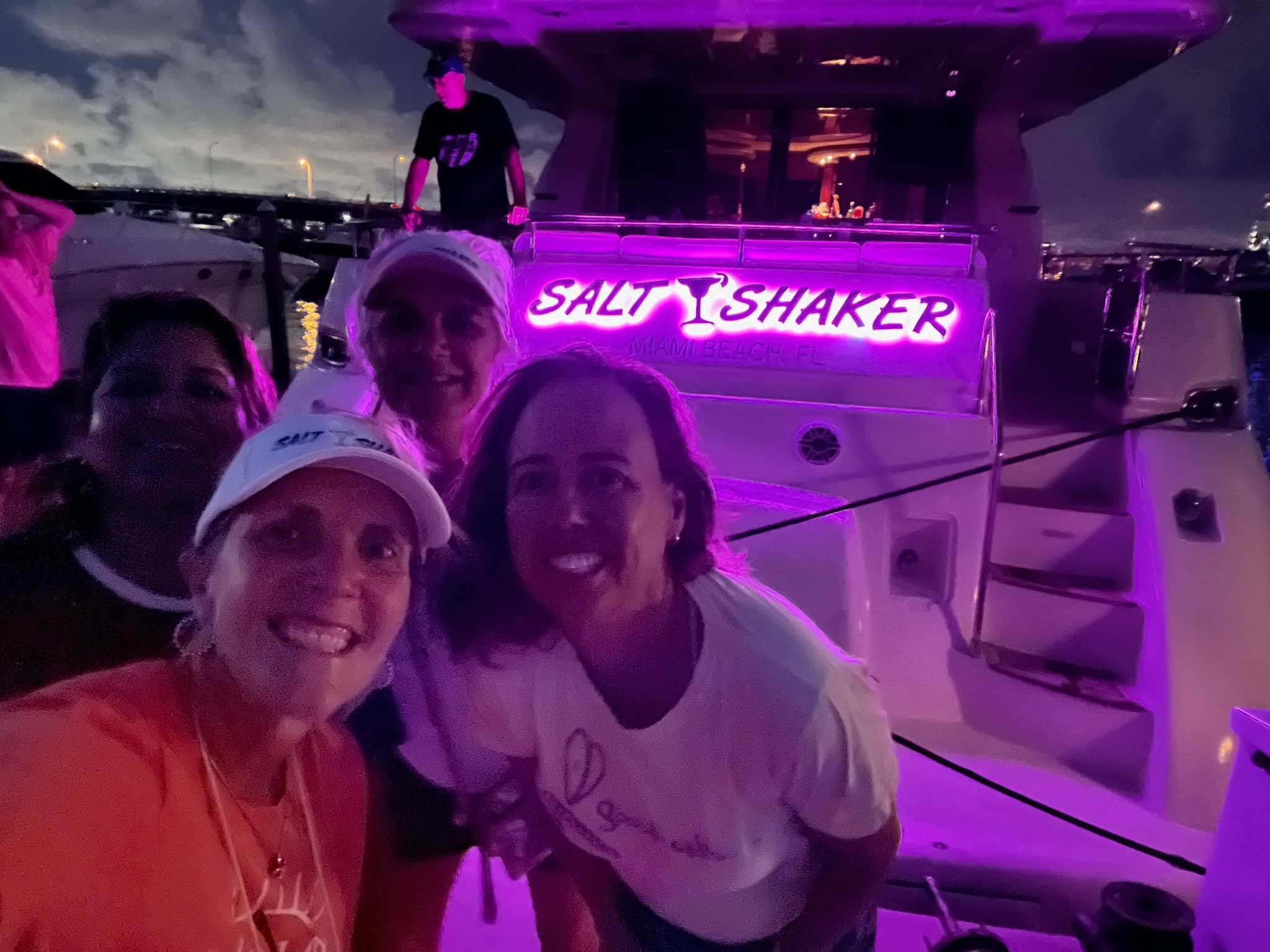 Night boat party on deck with purple lights and smiling crew