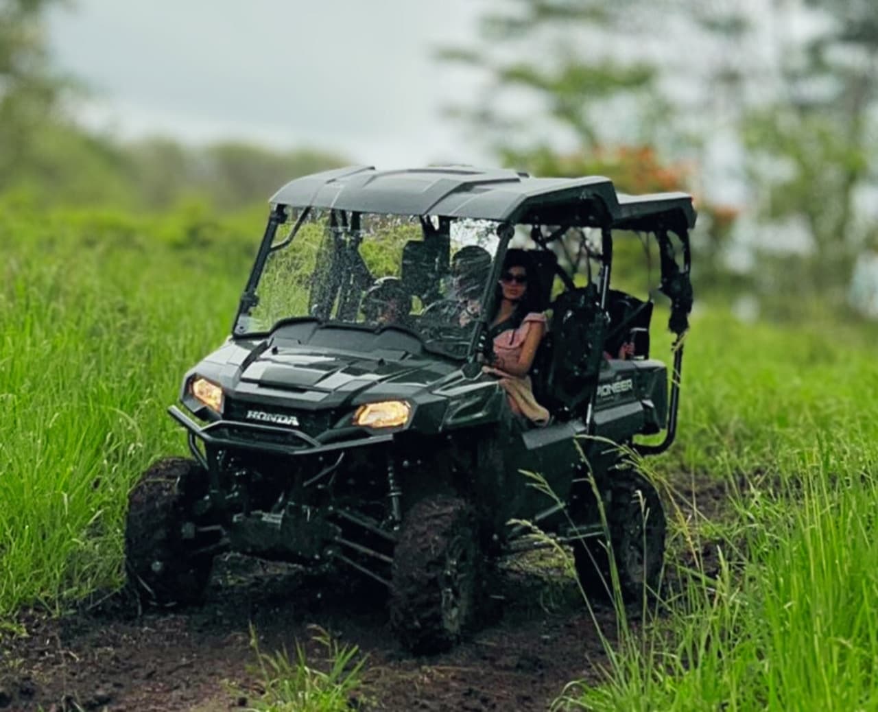 UTV crew navigating narrow grassy off-road trail through vegetation