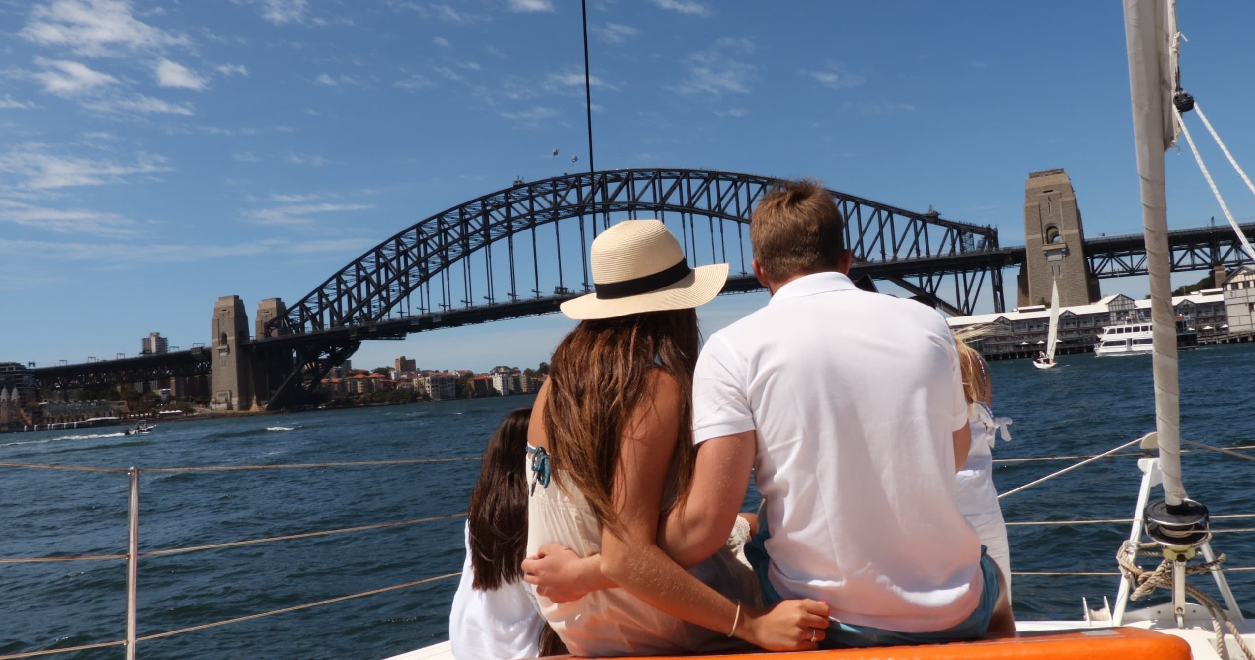 Couple sailing past Sydney Harbour Bridge on catamaran cruise