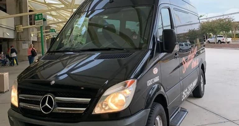Black Mercedes shuttle at airport curb showing pickup area