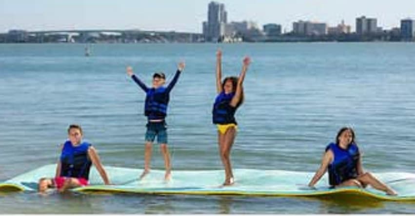 Children paddleboarding on calm city waterfront with skyline view