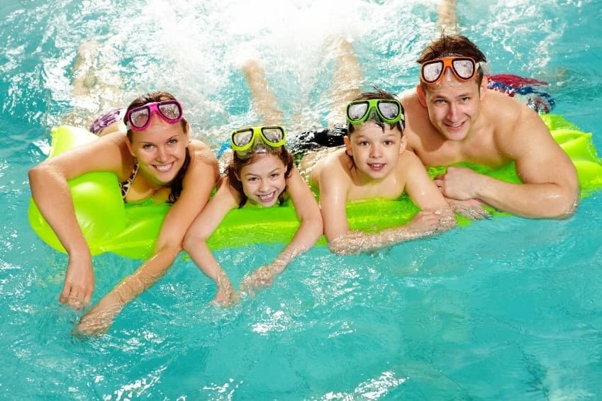 Family floating on inflatable in sunny outdoor pool