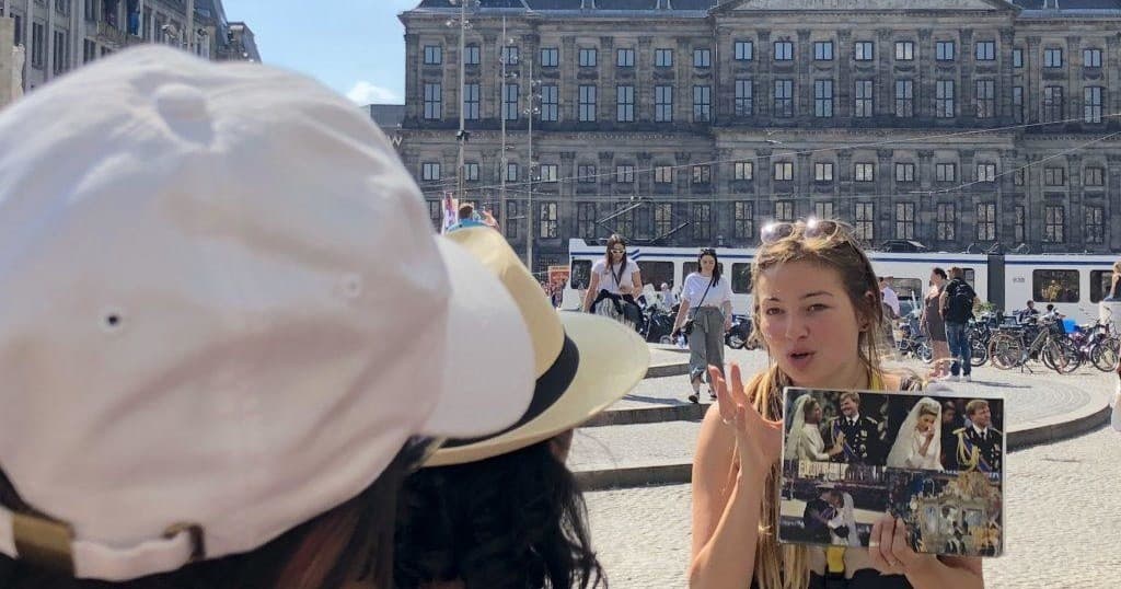 Guide showing photos to tourists at Amsterdam square outdoor tour