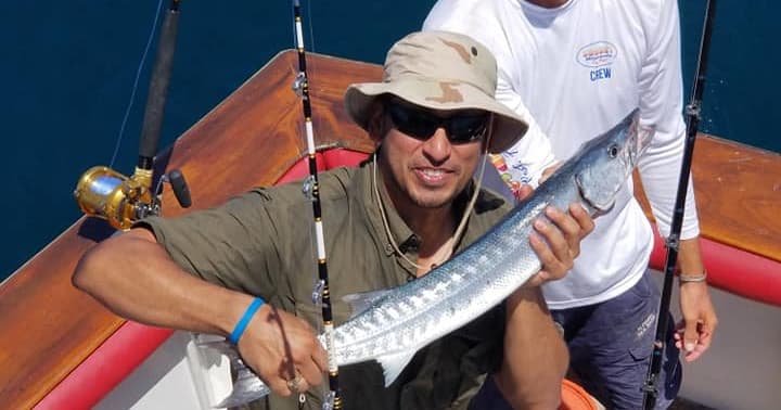 Fisherman displaying long barracuda aboard offshore sportfishing boat