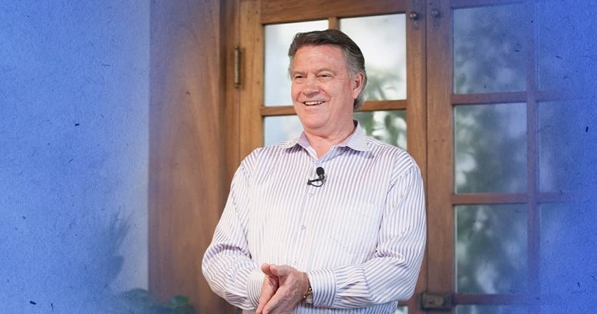 Presenter smiling near wooden doorway during indoor talk event
