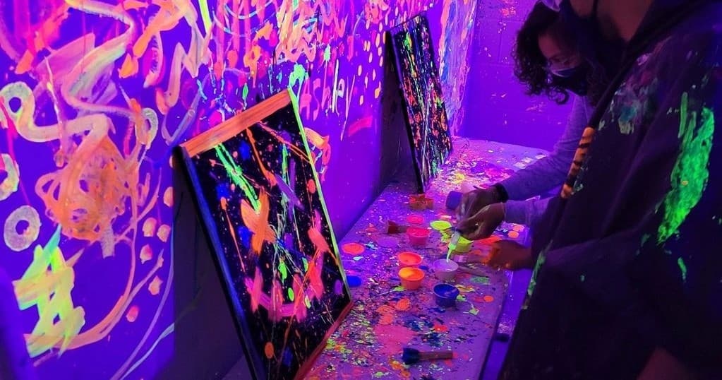 Blacklight paint studio in indoor rage room with neon art