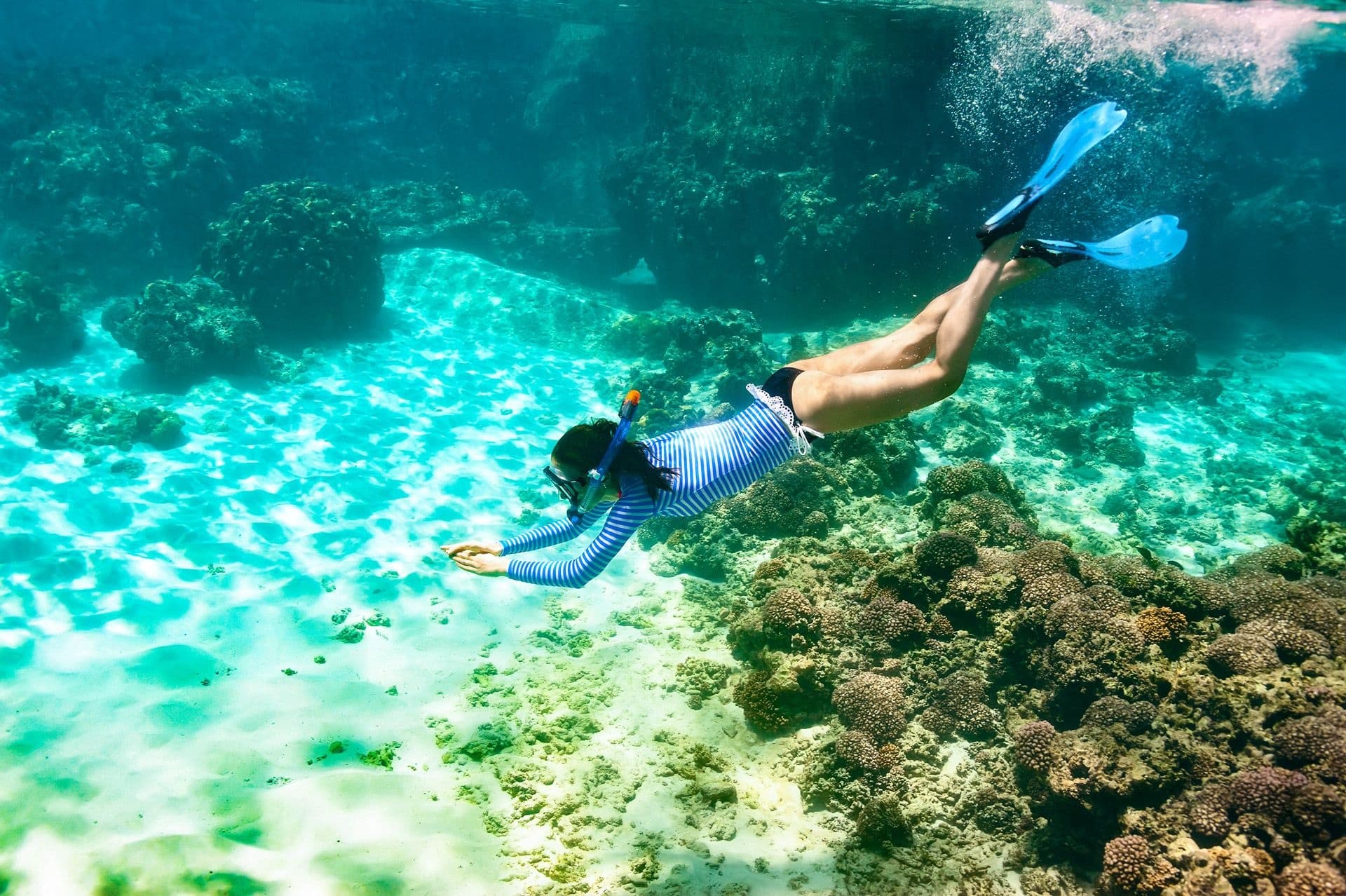 Snorkeler diving over coral reef in clear tropical waters