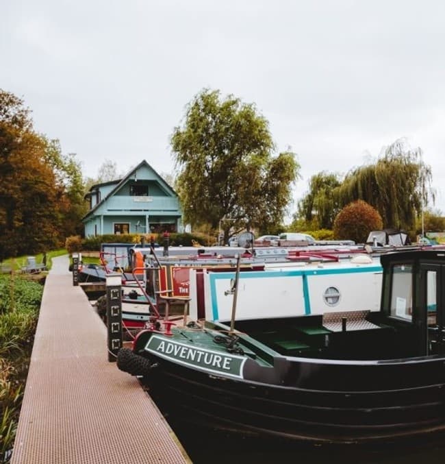 Moored narrowboats at Tattenhall Marina dock with autumn trees
