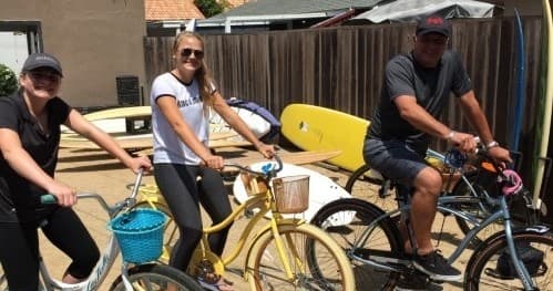 People riding beach cruiser bikes along sunny boardwalk