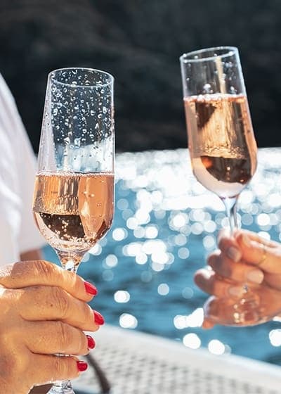 Two people toasting with champagne on boat, coastal celebration cruise