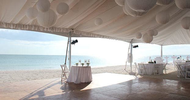 Beach event tent on sandy shore with ocean horizon view