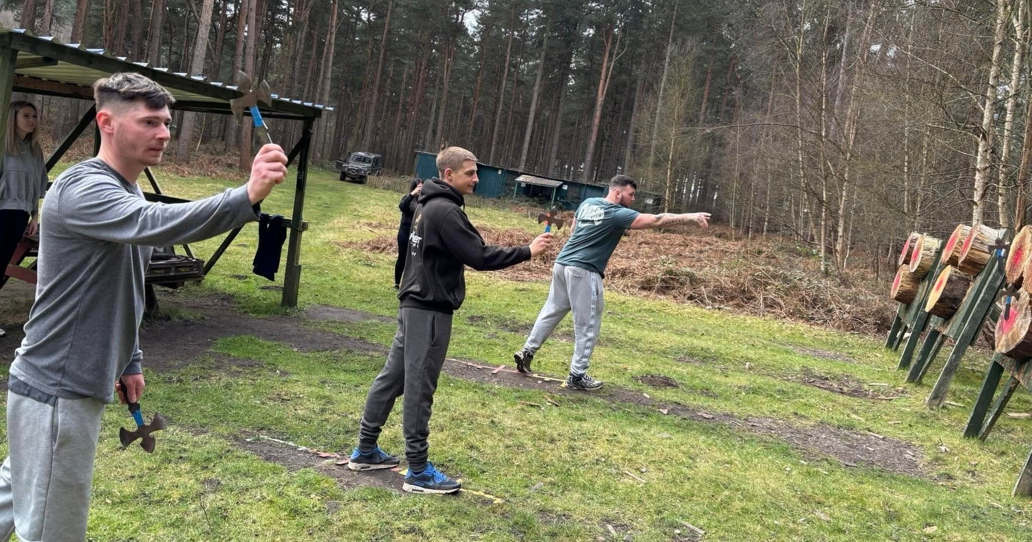 Archers aiming at outdoor targets on grassy woodland archery range