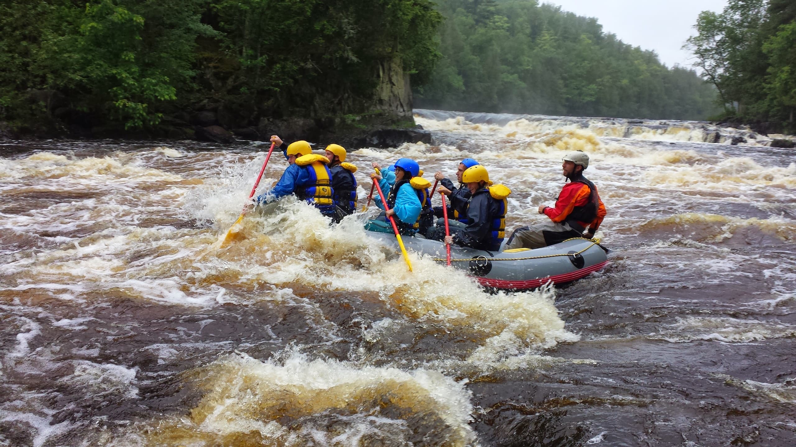 Rafting group navigating fast river rapids in forested canyon