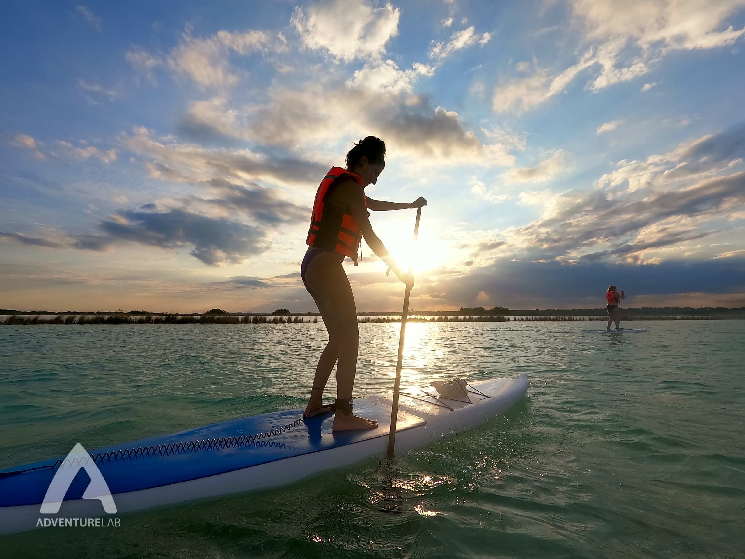 Sunset paddleboarding silhouette on calm tropical waters