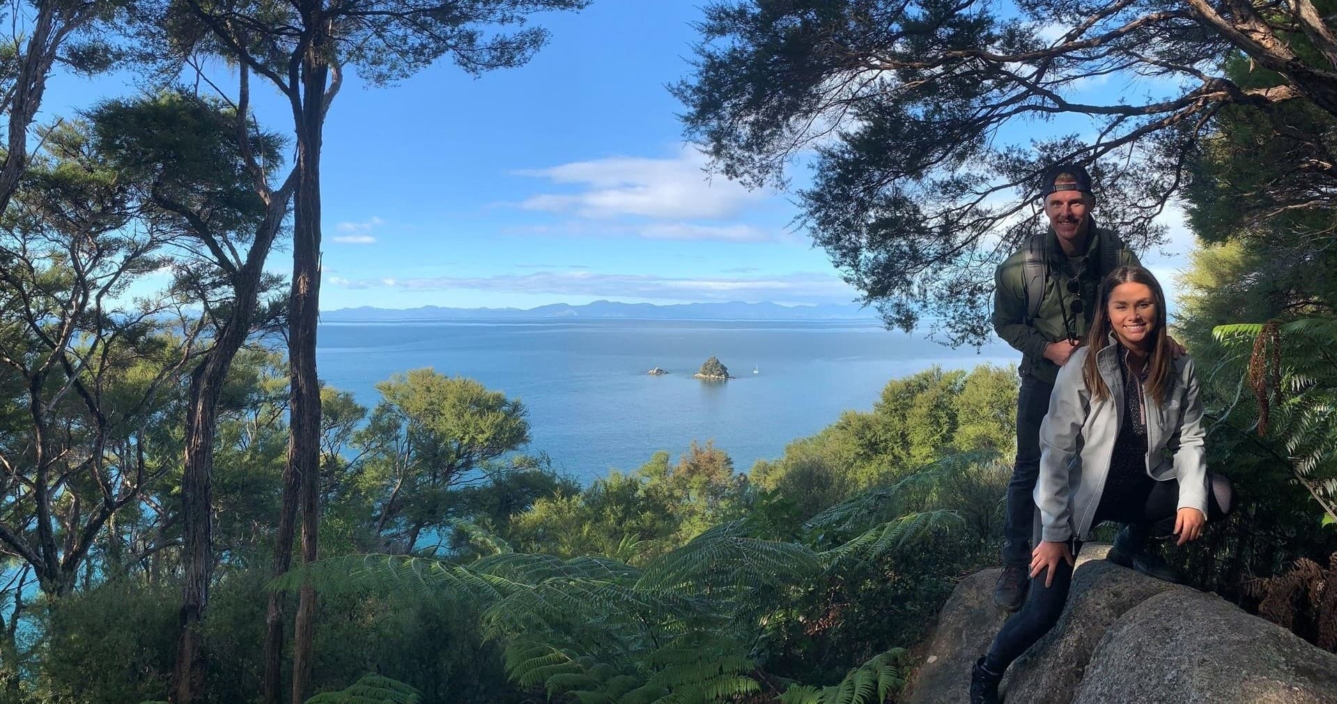 Hikers posing on coastal lookout overlooking island-studded bay