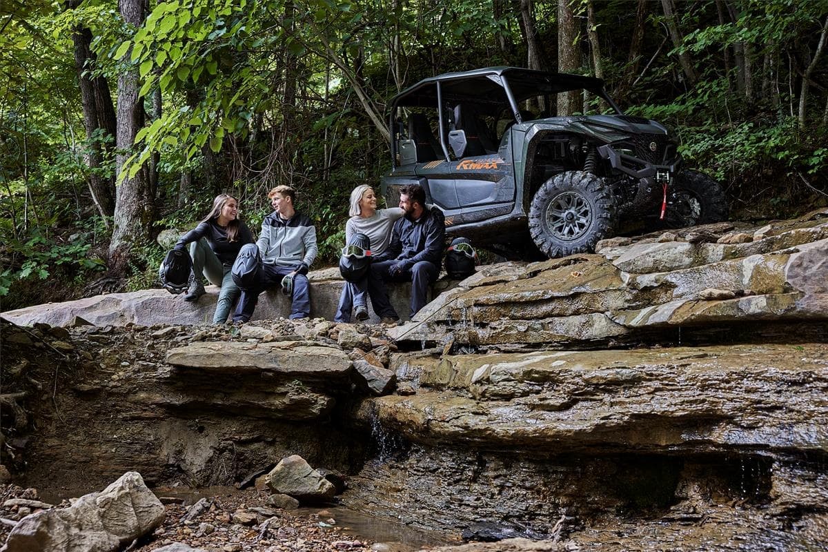 Group with side-by-side UTV relaxing on rocky forest overlook