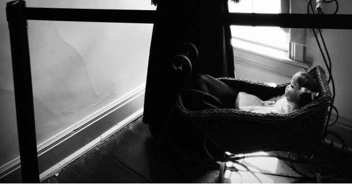 Antique doll resting in wicker cradle inside haunted museum