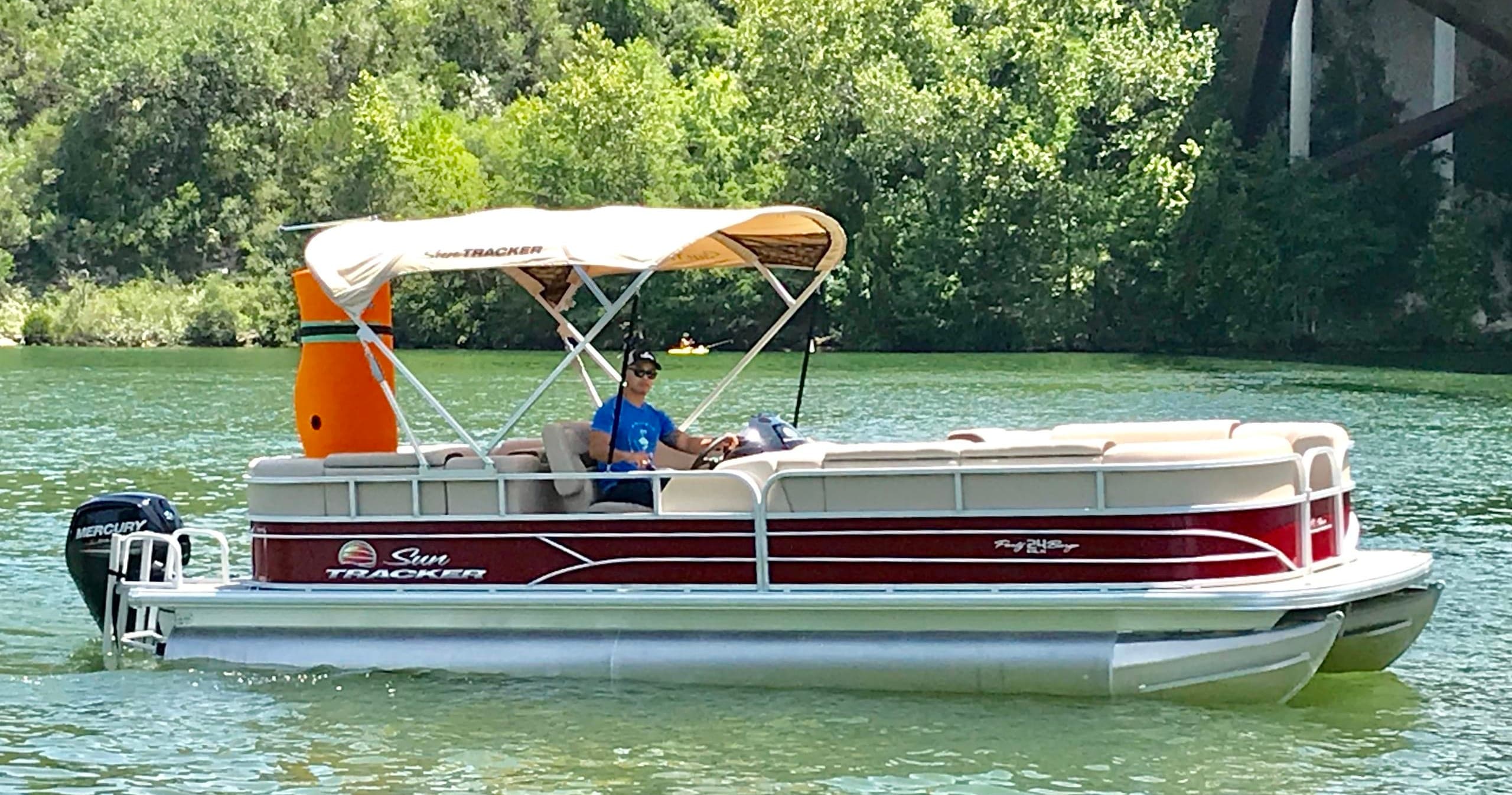 Pontoon boat cruising on calm green lake with canopy
