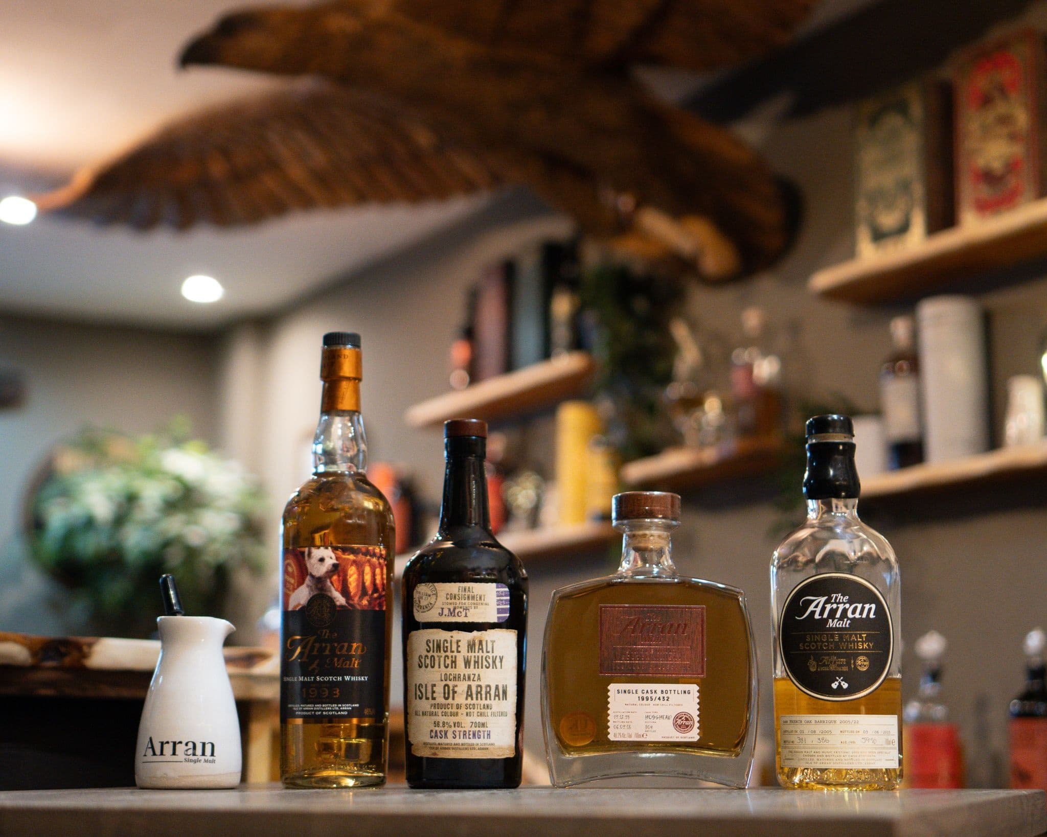 Whisky tasting flight bottles displayed on bar in cozy distillery