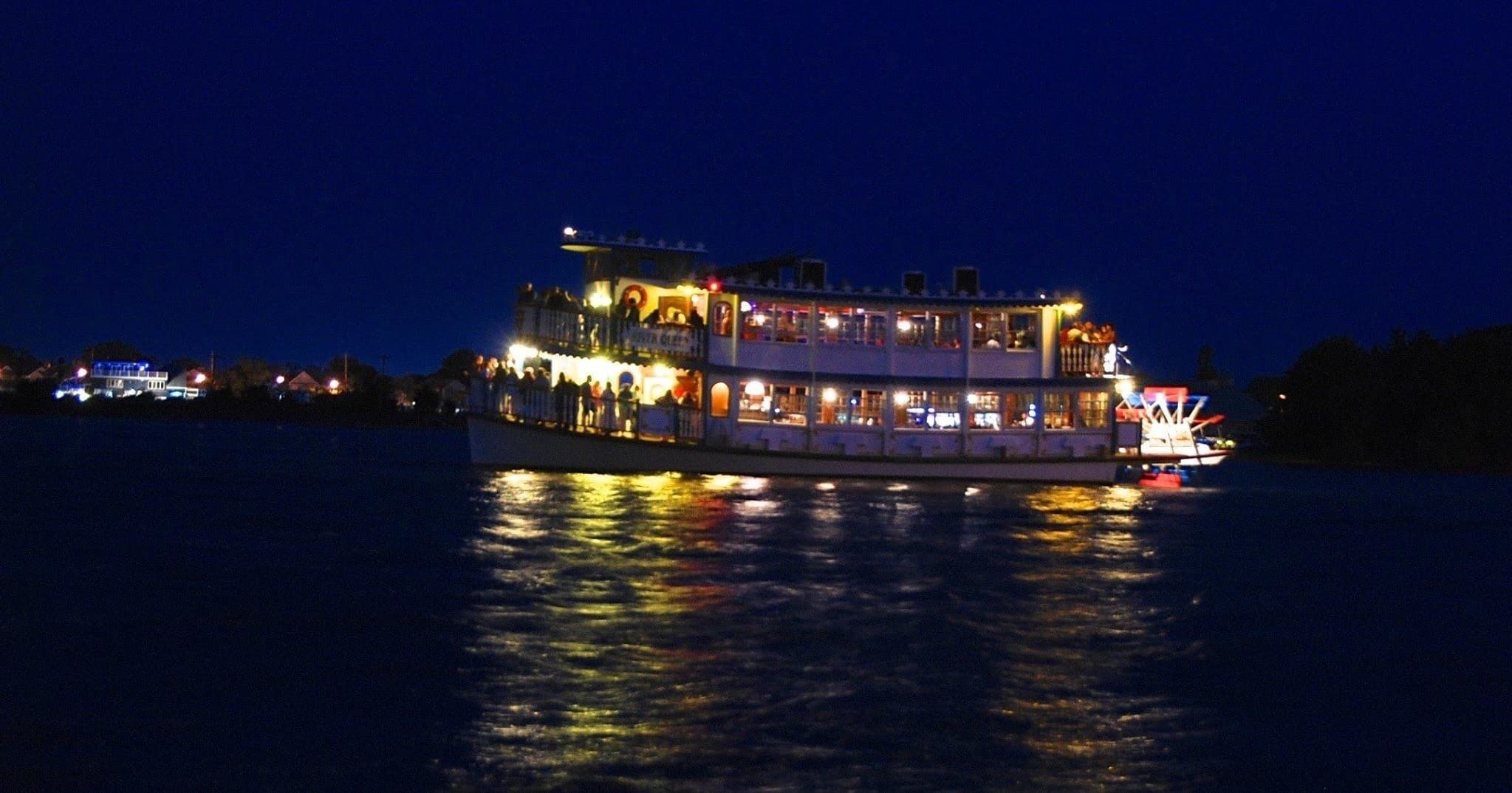 Illuminated riverboat cruising at night on calm water sightseeing