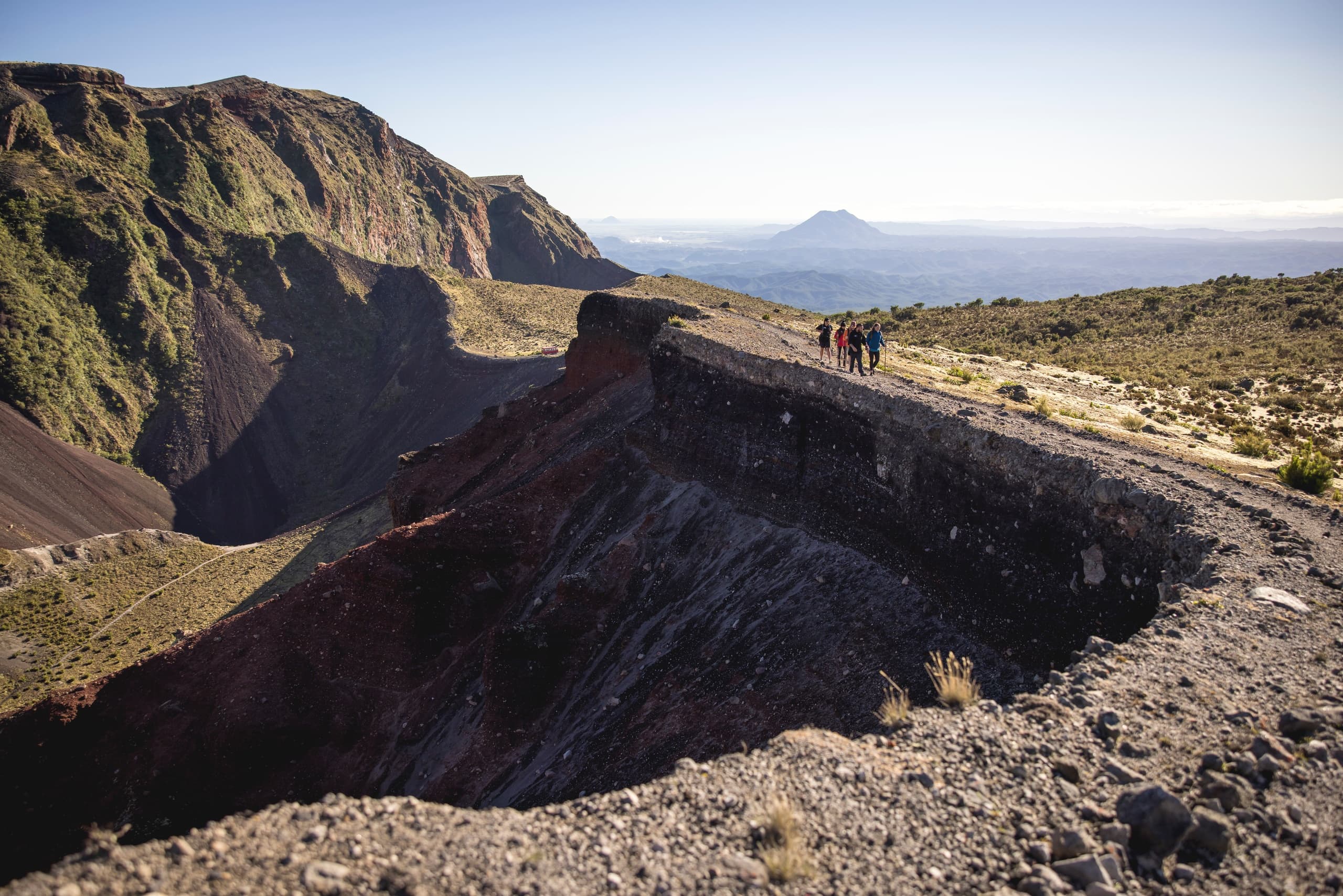 Scenic volcanic crater rim and rugged valley with distant peak
