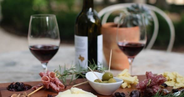 Wine glasses and charcuterie on outdoor patio with bottle