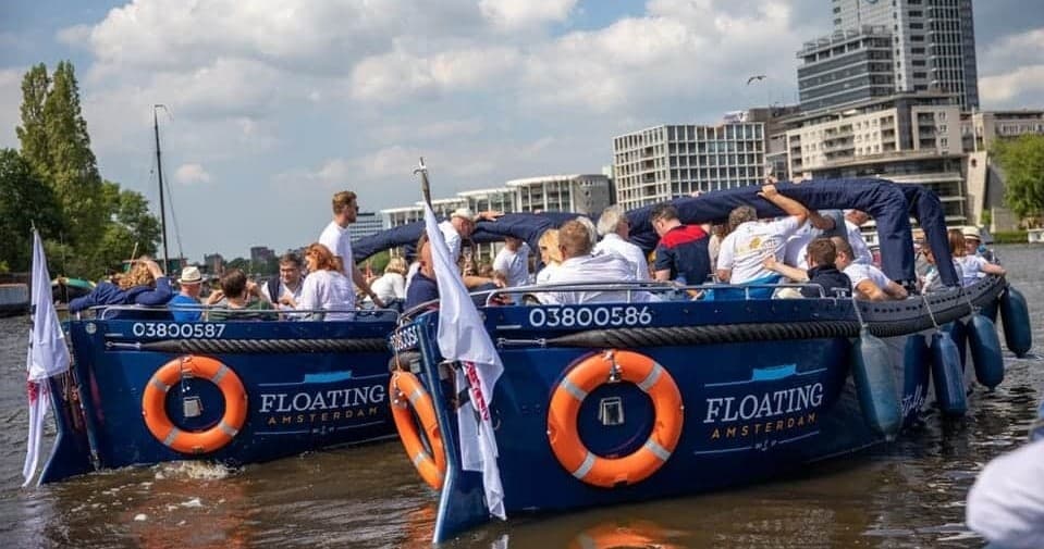 Group canal boat tour with passengers enjoying sunny Amsterdam ride