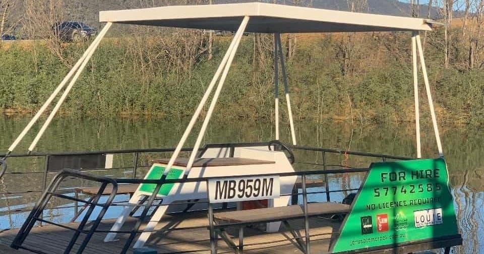 Covered pontoon boat moored on riverbank for hire, calm water