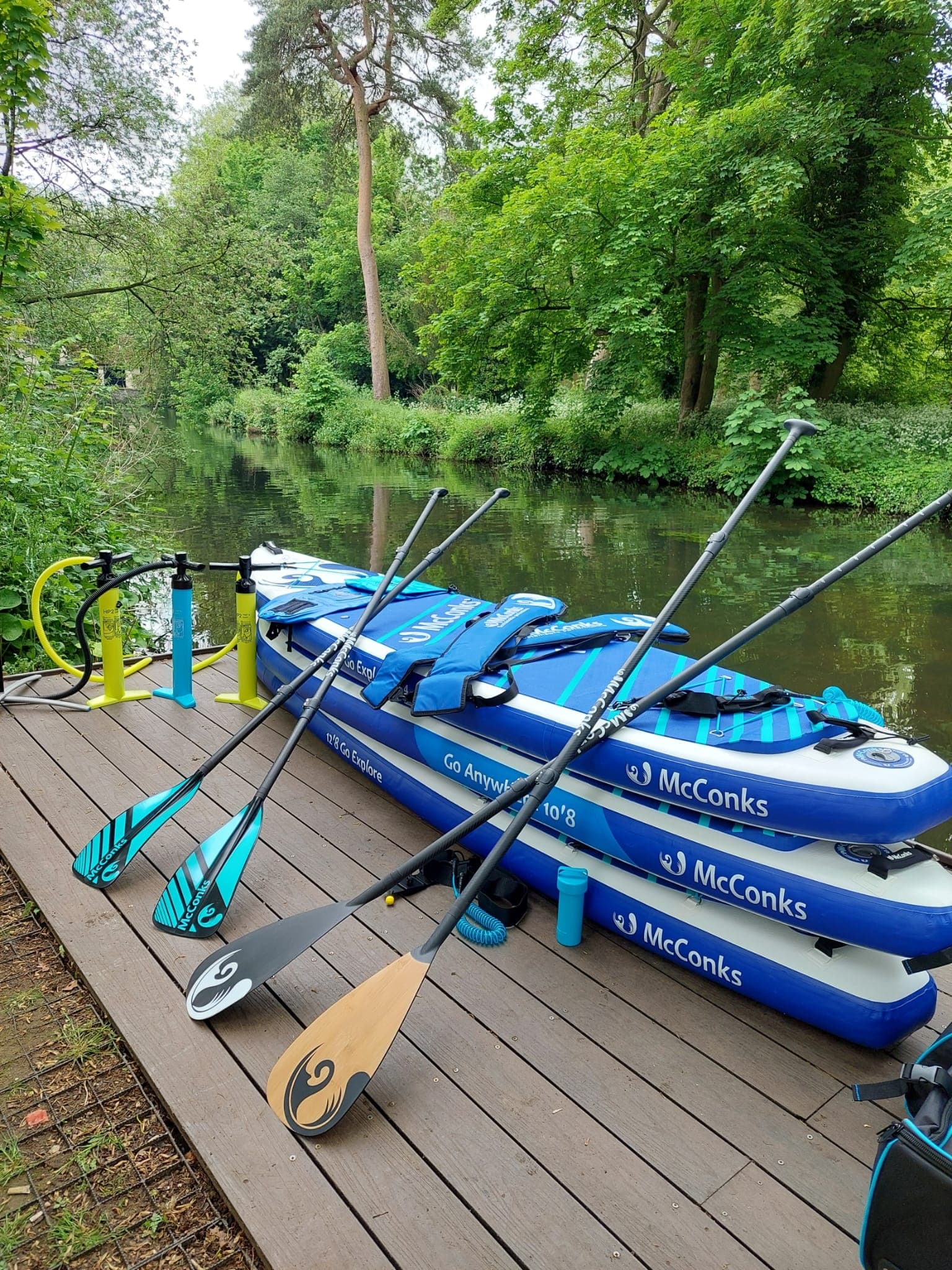 Stacked inflatable kayaks and paddles on wooden dock by river