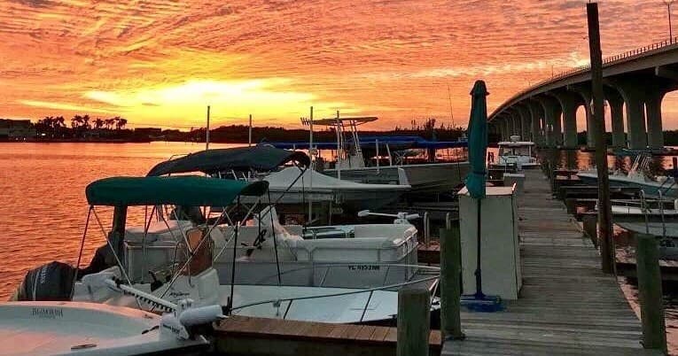 Boats docked at marina at sunset, waterfront scenic pier view