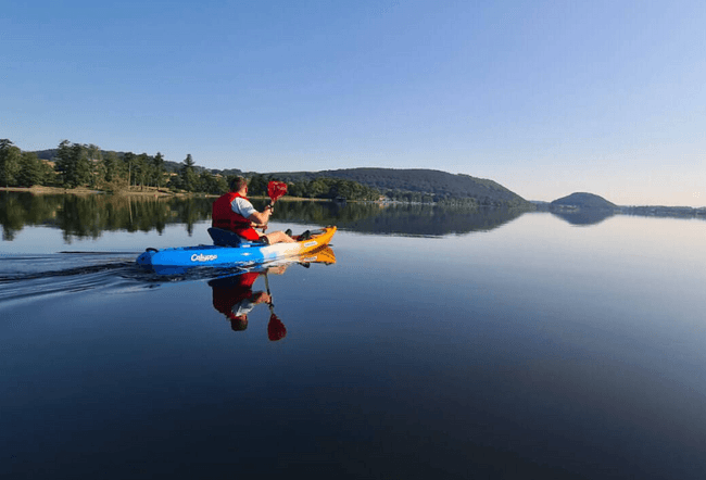 Solo kayaker gliding on glassy lake toward distant islands