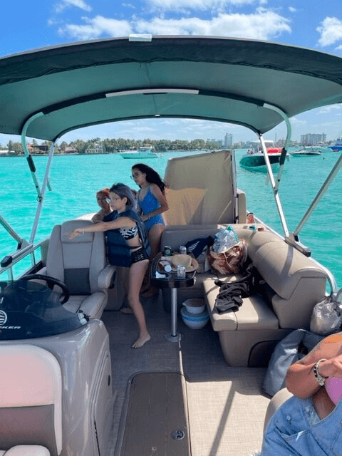 Friends enjoying pontoon cruise over turquoise waters, anchored bay