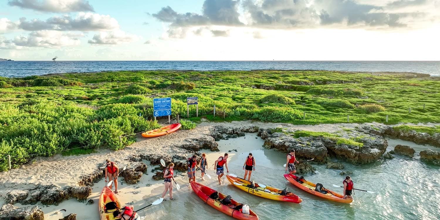 Two-person kayak gliding above coral reef in shallow Hawaiian waters