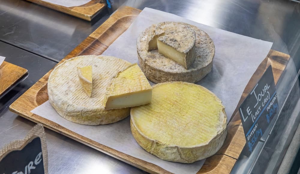 Assorted artisanal cheeses on wooden boards at market counter
