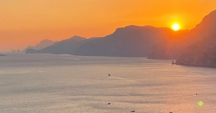 Sunset over Mediterranean coastline with distant mountains