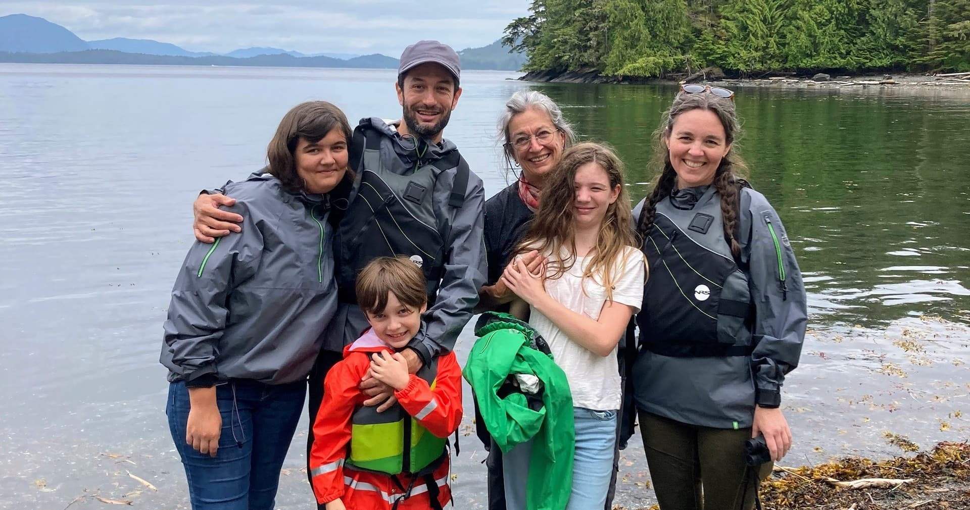 Family kayakers on rocky Alaskan shoreline after paddling trip