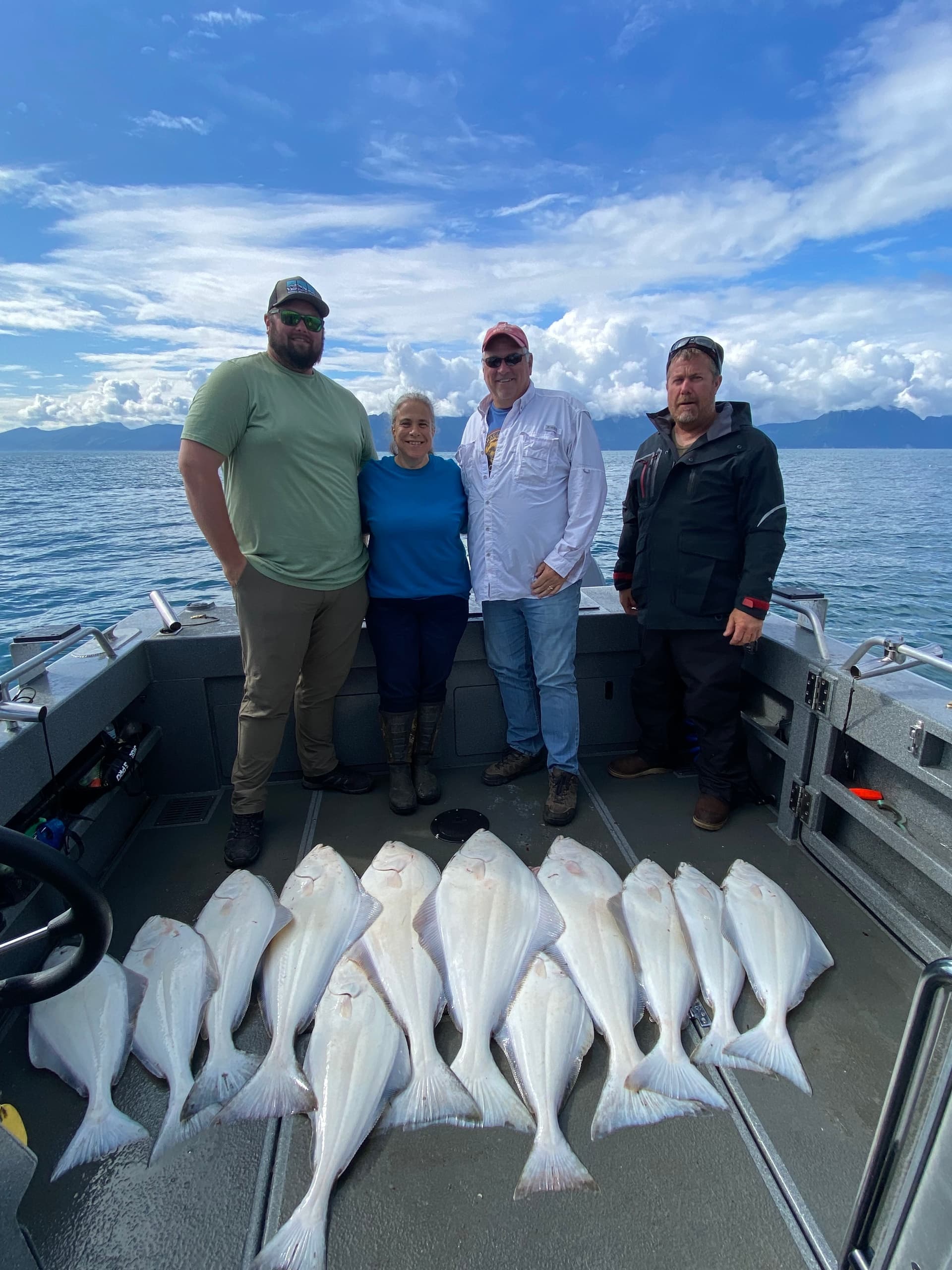 Charter anglers posing with halibut aboard boat under blue sky
