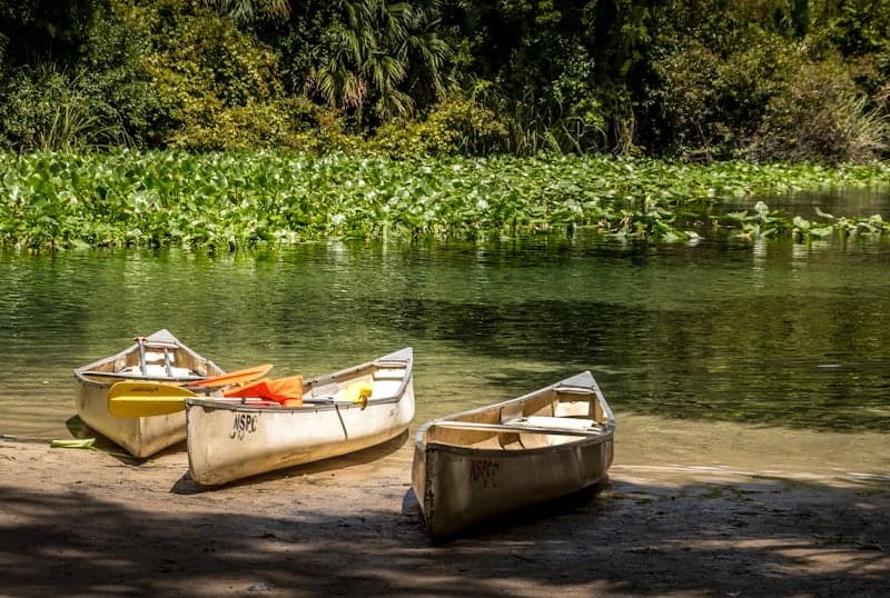Three canoes resting on sandy shore of a quiet lake