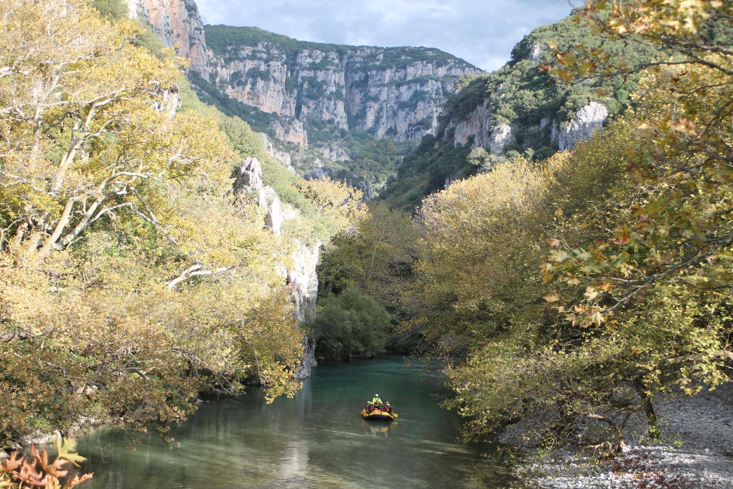 Calm river gorge with small raft navigating tree-lined canyon