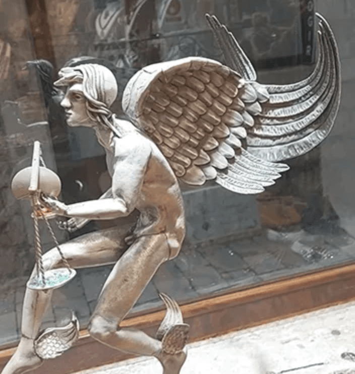 Bronze winged statue displayed in shop window on street