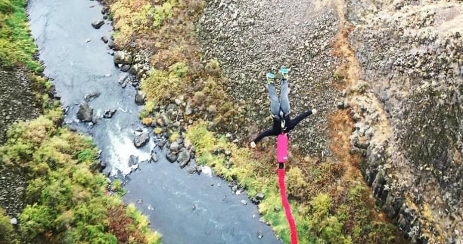 Bungee jumper falling over river through scenic canyon gorge