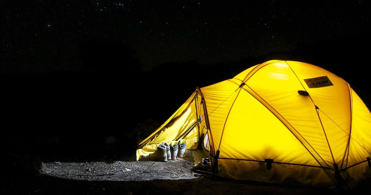 Illuminated yellow tent at night in remote campsite