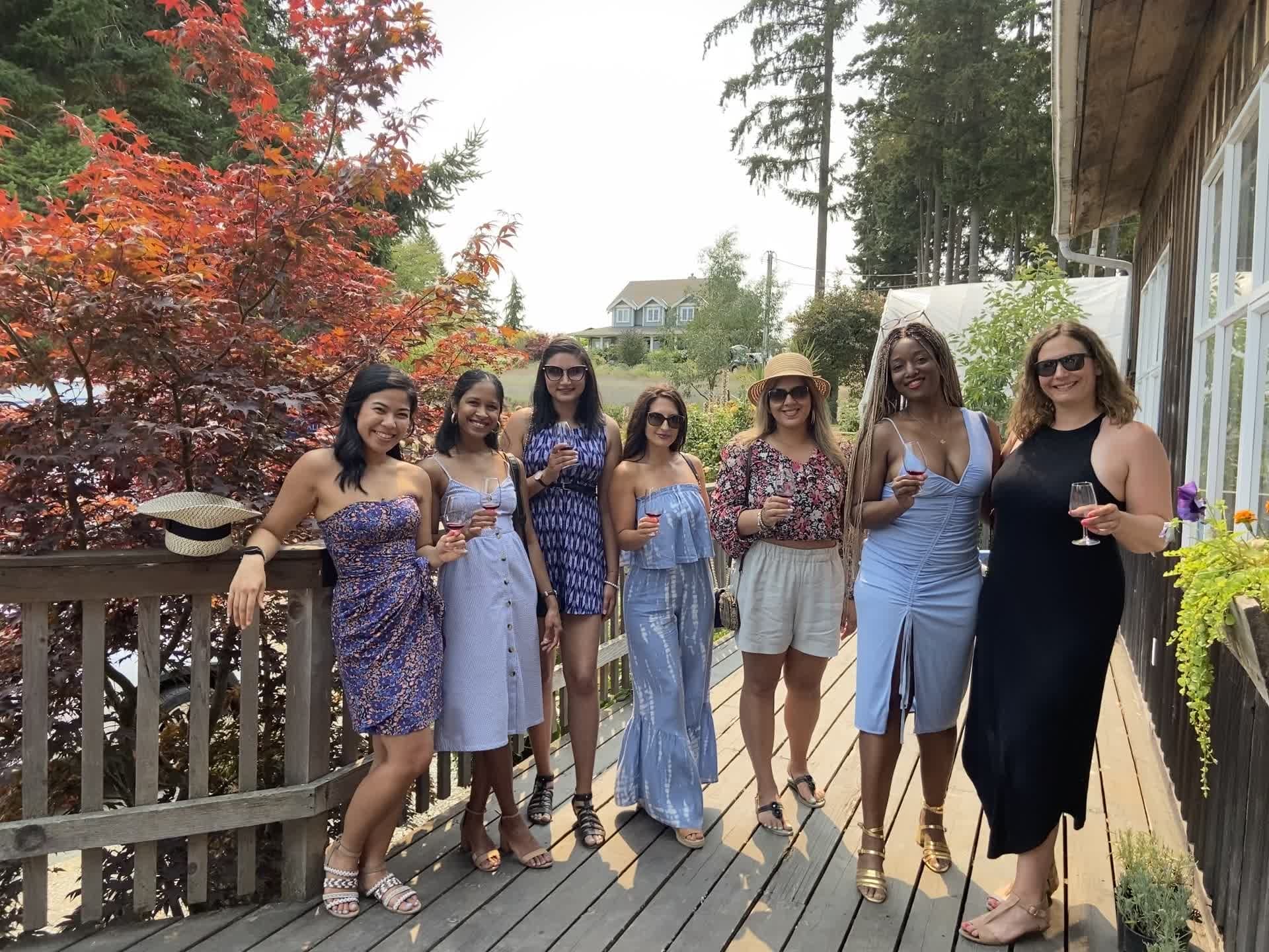 Group of friends on forested waterfront deck enjoying drinks