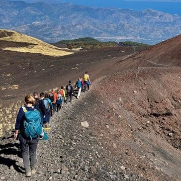 Hikers trekking a volcanic slope on Mount Etna trail