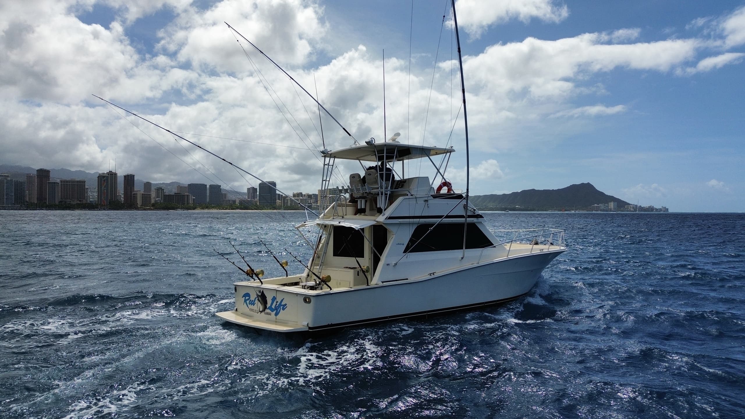 Sportfishing boat under cloudy sky with coastal skyline